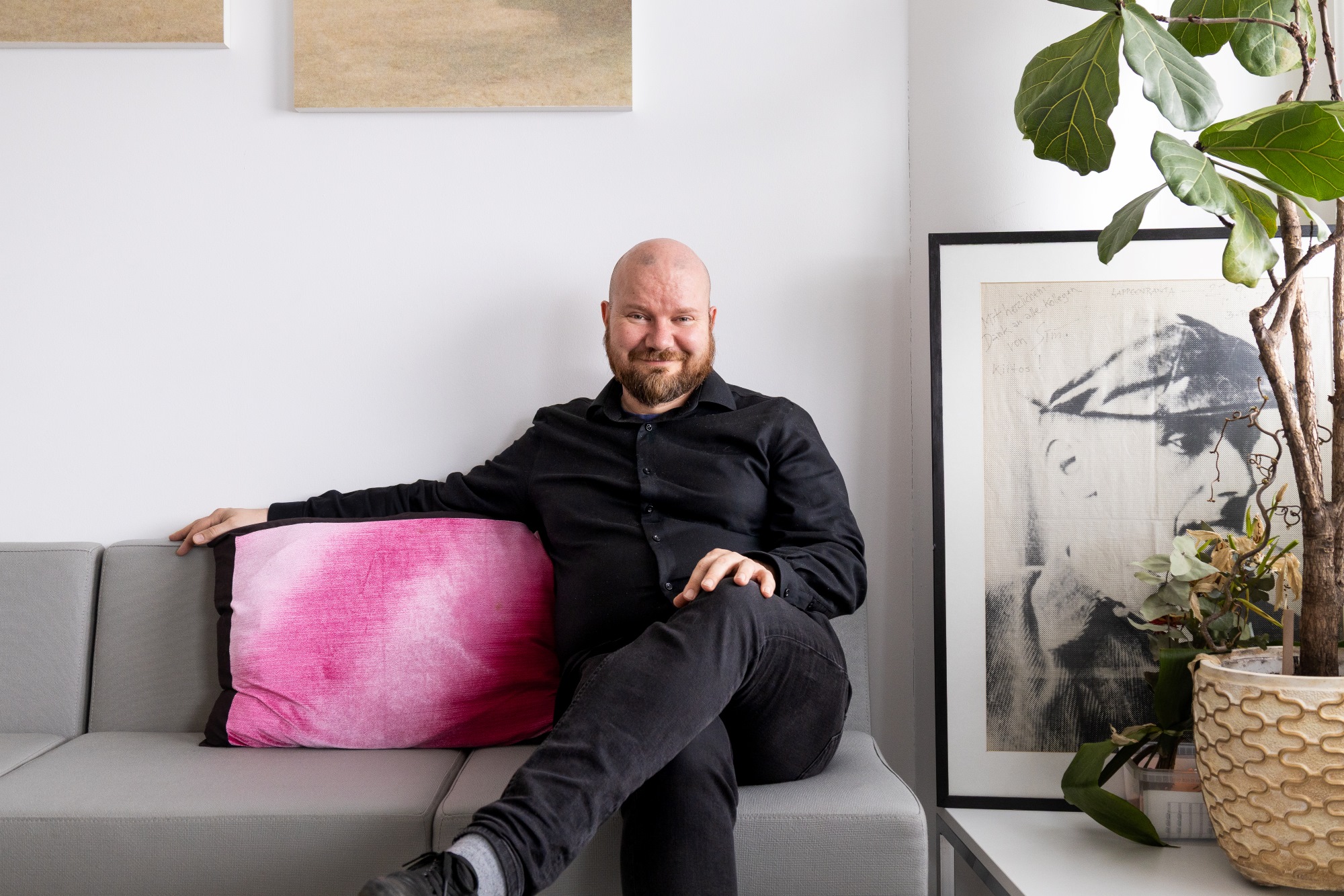 Tuomo Rämö istuu sohvalla hymyillen.